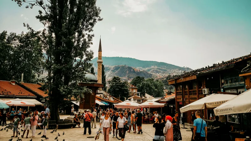 The Bascarsija square busy with people beneath a minaret and the surrounding hills