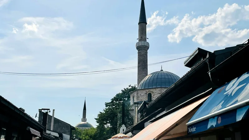A mosque dome and minaret rising above a Sarajevo street