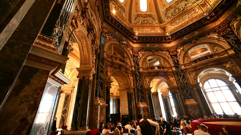 An ornate historic interior with café tables and vaulted ceilings
