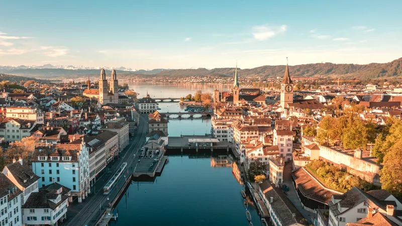 The Limmat running through Zurich with church towers, the lake and the Alps beyond